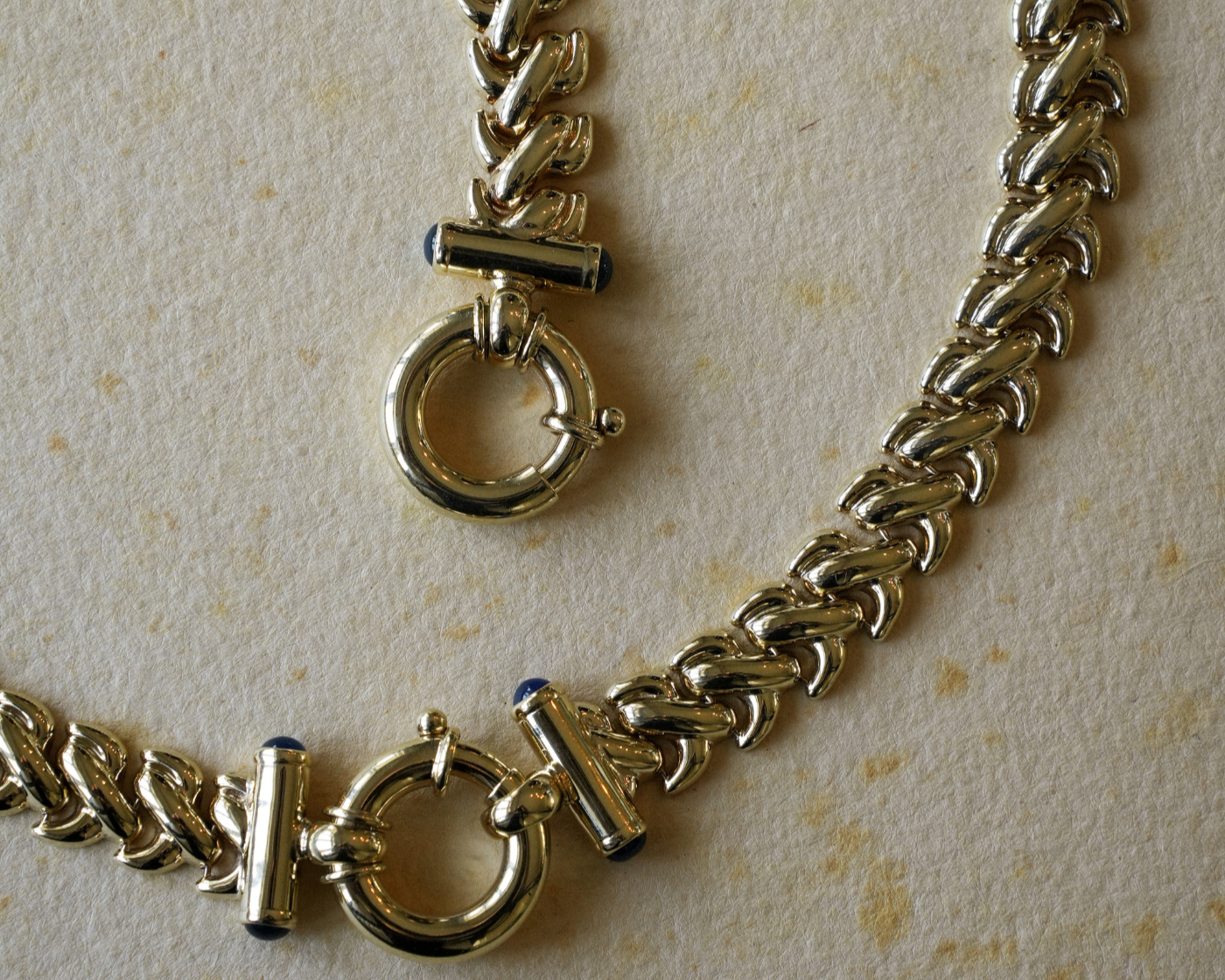 Gold chain necklace with clasp on a beige background