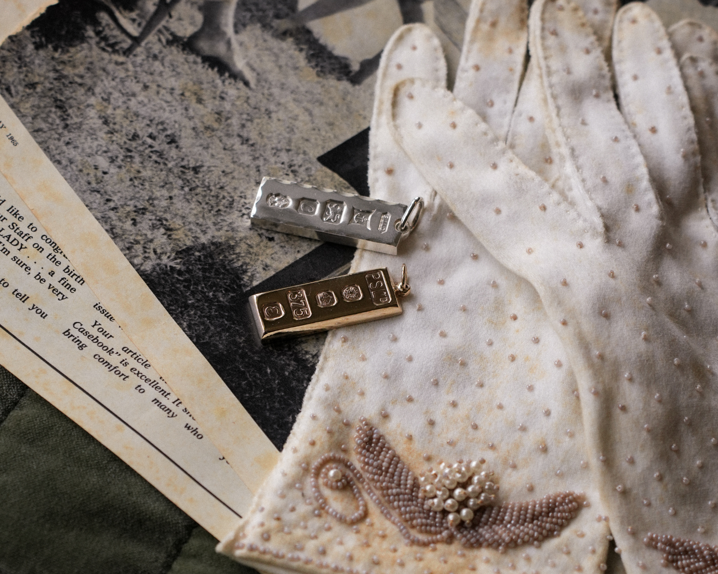 Pair of white gloves with decorative brooches on a textured surface with an old letter.